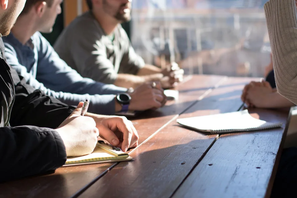 Colleagues around a table with notepads, talking through how they work together